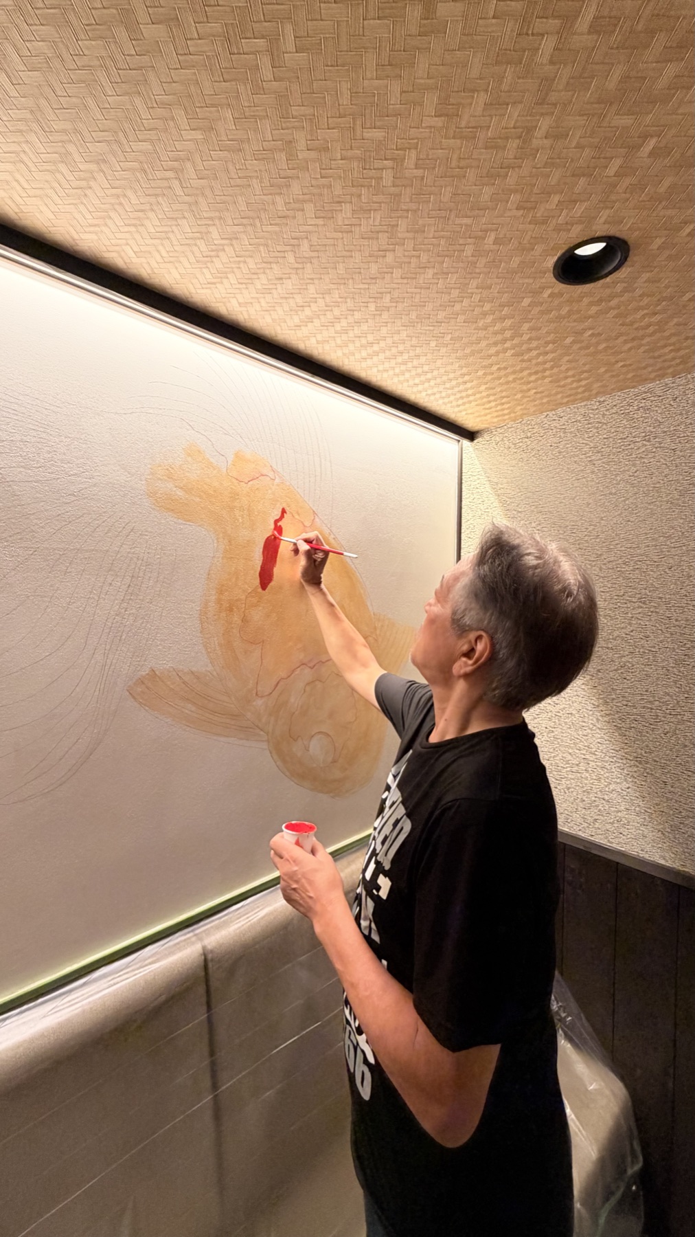 赤い金魚の壁画を制作する中村哲叡